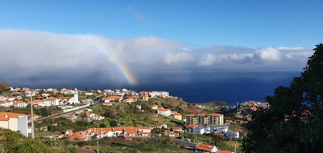 A rainbow over a town on Madeira's coast