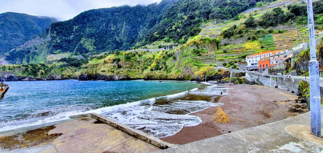 The beach and natural pool at Seixal below green mountains