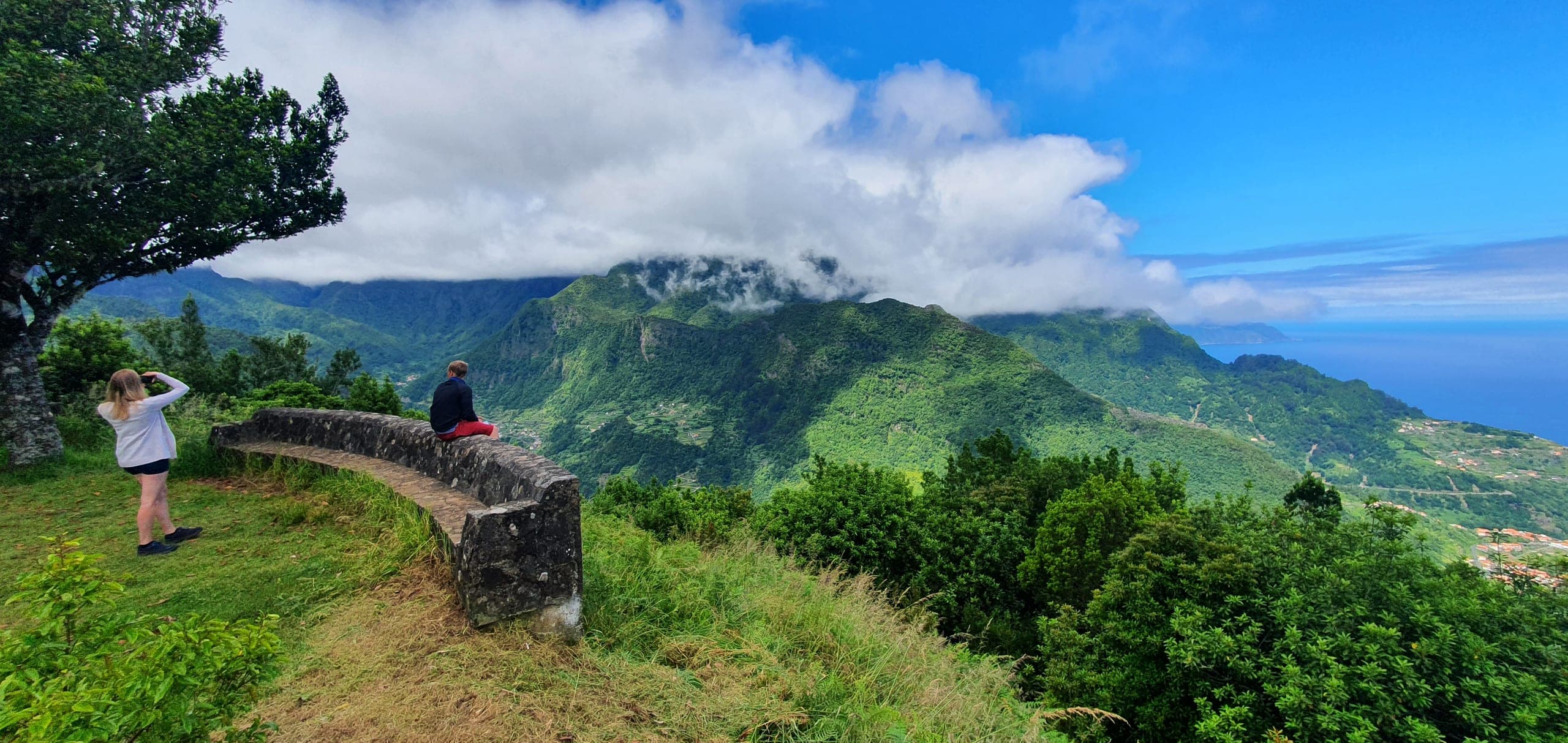 Tour guests at a north-coast viewpoint looking over Madeira's green mountains