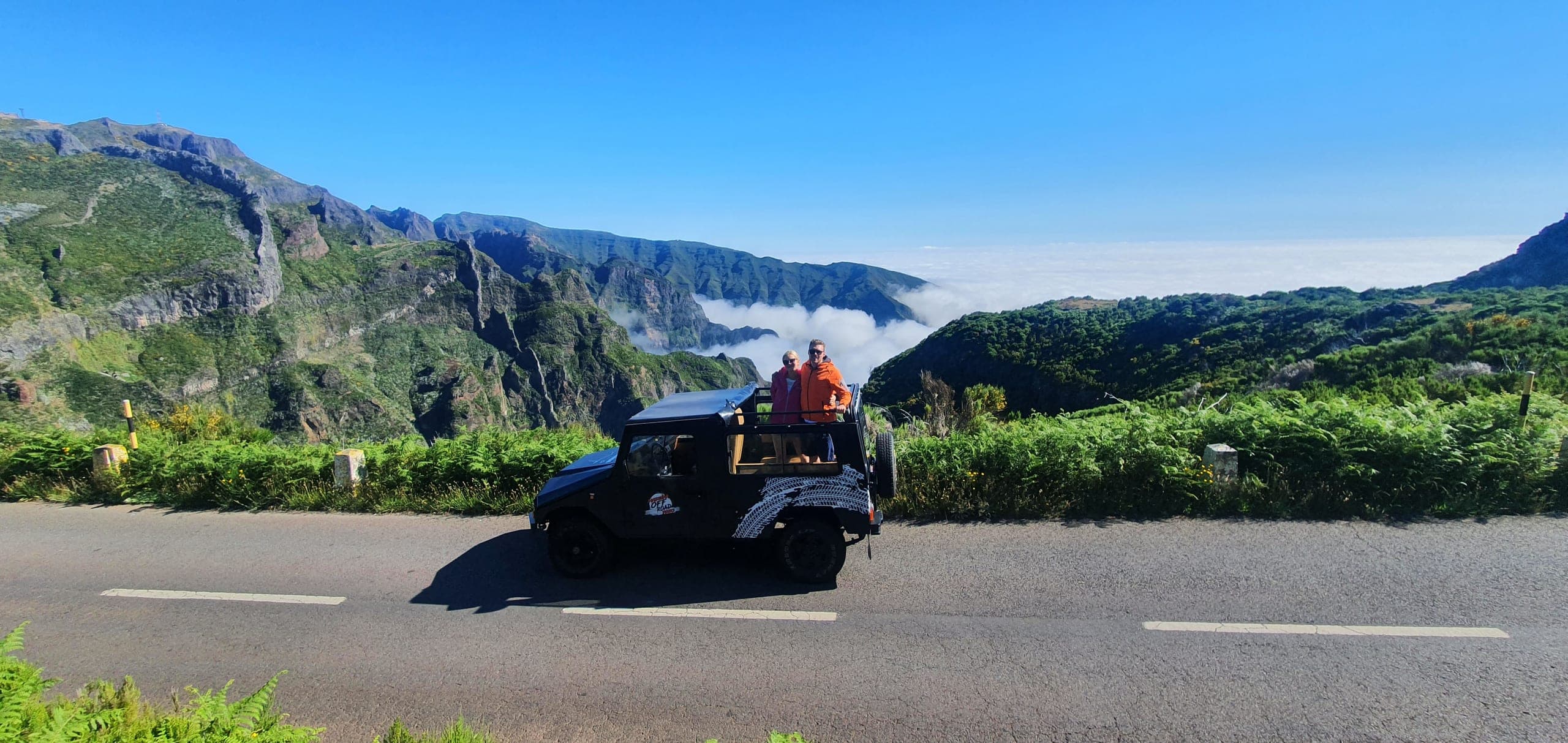 Guests standing in the Madeira Off Road Jeep on a mountain road above a sea of clouds